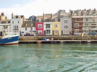 A waterfront with colorful houses and a boat docked at Amaranta Brewers Quay Harbour
