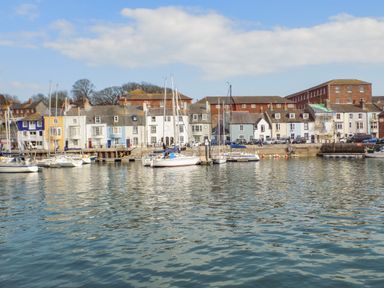 A harbor with sailboats docked near a row of colorful buildings at Amaranta Brewers Quay Harbour
