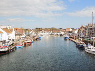 A harbor with boats docked along both sides and buildings lining the waterfront at Amaranta Brewers Quay Harbour
