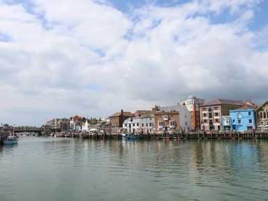A waterfront with buildings and boats along the shore at Amaranta Brewers Quay Harbour