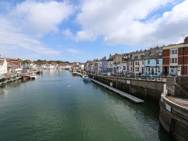 A harbor with boats docked along the sides and buildings lining the waterfront at Amaranta Brewers Quay Harbour