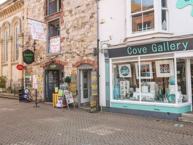 A street view showing Londis Harbour Stores and Cove Gallery with items displayed in the shop windows at Amaranta Brewers Quay Harbour