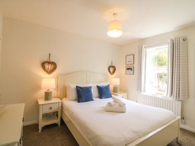 A bedroom with a white bed frame blue pillows bedside tables lamps and striped curtains at Amaranta Brewers Quay Harbour