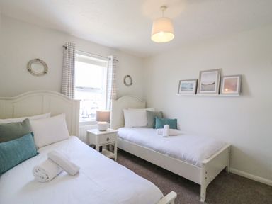A bedroom with two single beds a nightstand between them and framed pictures above one bed at Amaranta in Brewers Quay Harbour