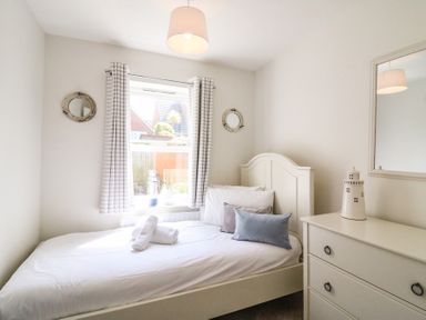 A bedroom with a single bed pillows towels and a dresser with a mirror at Amaranta in Brewers Quay Harbour
