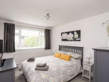 A bedroom with a bed with gray and yellow bedding and gray furniture at 31 Beach Road in Morfa Bychan
