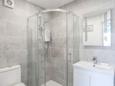 A bathroom with a corner shower enclosure a toilet a sink with a faucet and a mirror at 31 Beach Road Morfa Bychan