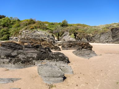 A sandy beach with large rocks and a wooden footbridge over a rocky area at 31 Beach Road in Morfa Bychan