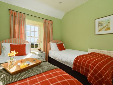 A bedroom with two single beds near a window at Three Chimneys in St Levan near Porthgwarra