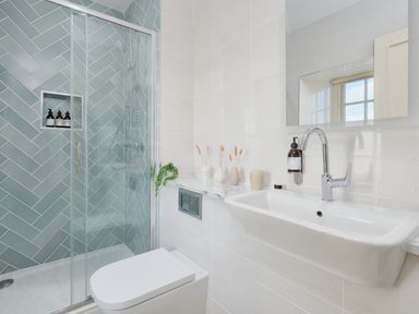 A bathroom with a toilet sink and shower with blue tiles at Three Chimneys in St Levan near Porthgwarra