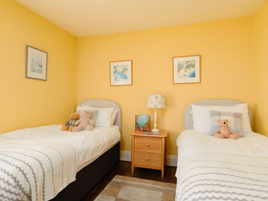 A bedroom with two single beds a wooden nightstand a table lamp and teddy bears at Higher Roskestal St Levan near Porthgwarra