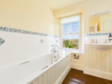 A bathroom with a bathtub sink window and plants at Higher Roskestal in St Levan near Porthgwarra