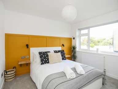 A bedroom with a double bed and yellow paneling on the wall at Dolwyn in Llandegfan
