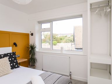 A bedroom with a bed near a window and a small indoor plant at Dolwyn in Llandegfan