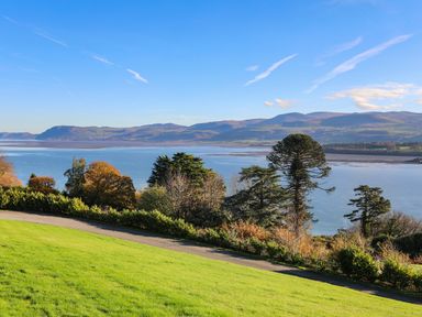 A view of a body of water with trees and hills in the background at Dolwyn in Llandegfan