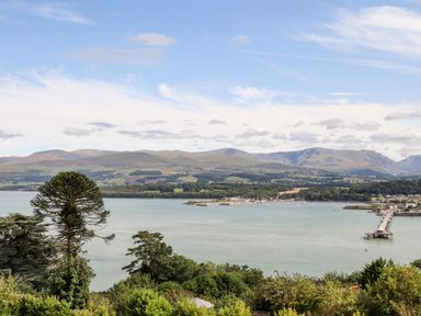 A coastal view with water trees and mountains in the background at Dolwyn in Llandegfan