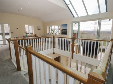 An open dining and sitting area with a wooden railing and large skylight at Tan Twr in Llanfairpwll