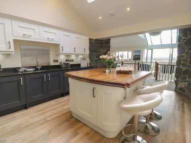 A kitchen with an island with barstools and flowers on it at Tan Twr in Llanfairpwll