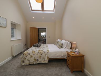 A bedroom with a bed a bedside table and a skylight at Tan Twr in Llanfairpwll
