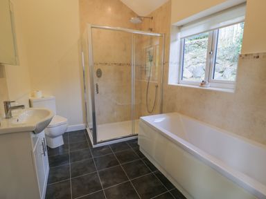 A bathroom with a bathtub a glass shower enclosure a toilet and a sink at Tan Twr in Llanfairpwll