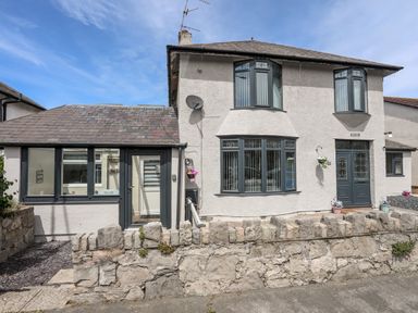 A two-story house with bay windows and a stone wall in front at Beeches Bach in Prestatyn