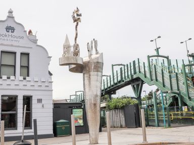 A metal sculpture near a white building and a green pedestrian bridge at Beeches Bach in Prestatyn