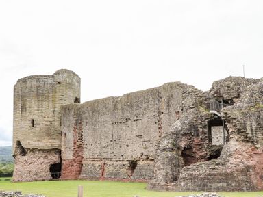 An old stone castle ruin with a round tower and large walls on grass at Beeches Bach in Prestatyn
