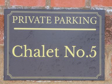 A black and yellow private parking sign for Chalet No 5 on a brick wall at Chalet 5 in Sherburn