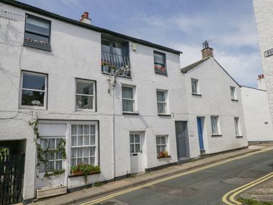A street with white terraced houses and flower boxes on windows at The Old Mill in Keswick