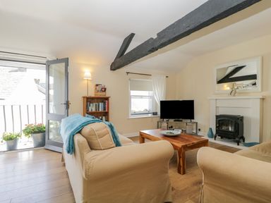 A living room with beige sofas wooden coffee table tv and bookshelf at The Old Mill in Keswick