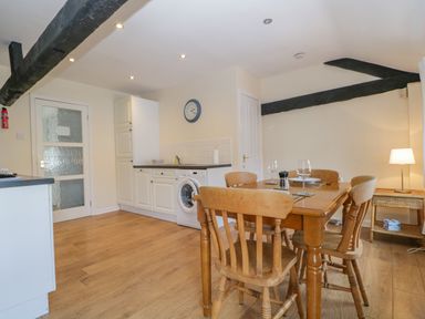 A kitchen with wooden dining table and chairs a washing machine and a clock on the wall at The Old Mill in Keswick