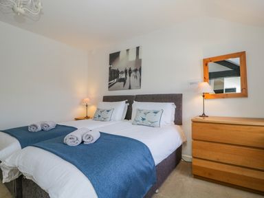 A bedroom with two single beds blue blankets and rolled towels on the bed at The Old Mill in Keswick