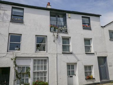 A white multi-story building with several windows and flower pots outside at The Old Mill in Keswick