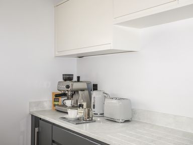 A kitchen countertop with a coffee machine milk bottle kettle toaster and cups at 3 Ty Stabal in Pwllheli