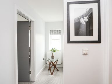 A hallway with a glass table and small plant near a window and a black and white framed picture on the wall at 3 Ty Stabal Pwllheli