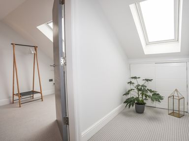 A room with a wooden clothes rack and hangers and an adjacent space with a potted plant and a glass lantern under a skylight at 3 Ty Stabal in Pwllheli