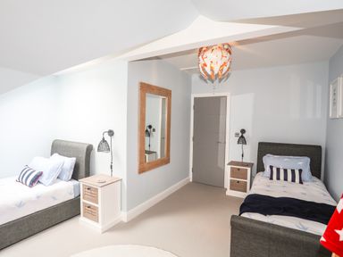 A bedroom with two single beds a door a wall mirror and two bedside tables at 3 Ty Stabal in Pwllheli