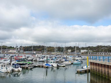 A marina with multiple small boats and yachts docked by piers with buildings and trees in the background at 3 Ty Stabal in Pwllheli