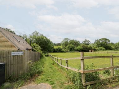 A pathway leading to a field near a building at The Shepherds Hut at Bridge Lake Farm & Fishery Chacombe