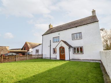 A white two-story house with a brown front door and multiple windows with a front lawn and a wooden fence at Ley Mill Farm in Huntley