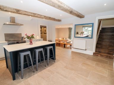 A kitchen with an island and stools and a dining area in the background at Ley Mill Farm in Huntley