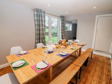A dining room with a wooden table set for six with plates glasses and cutlery at Ley Mill Farm in Huntley
