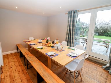 A dining room with a wooden table set for breakfast with chairs and benches at Ley Mill Farm in Huntley