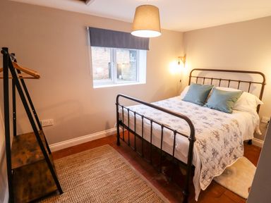 A bedroom with a metal bed frame blue cushions and a window with a blind at Ley Mill Farm in Huntley