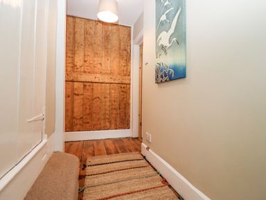 A hallway with wooden floorboards a woven rug a white pendant light and bird artwork on the wall at Ley Mill Farm in Huntley