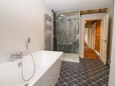A bathroom with a bathtub shower glass enclosure towel rack and patterned floor tiles at Ley Mill Farm in Huntley