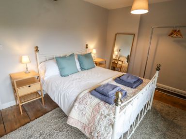 A bedroom with a white metal bed frame wooden bedside tables a mirror and a clothing rack at Ley Mill Farm in Huntley