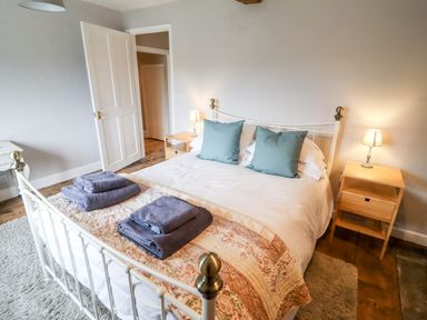 A bedroom with a white bed frame two blue pillows folded towels on the bed two wooden bedside tables with lamps at Ley Mill Farm in Huntley