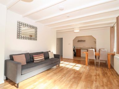 A living room with a sofa and dining area at Bracken Cottage St Tudy