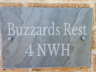 A stone wall with a grey plaque engraved with Buzzards Rest and 4 NWH at Buzzards Rest in Stannington near Morpeth